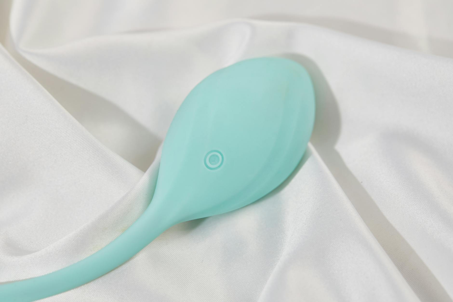 Stylish teal lemon clitoral vibrator on white silk fabric
