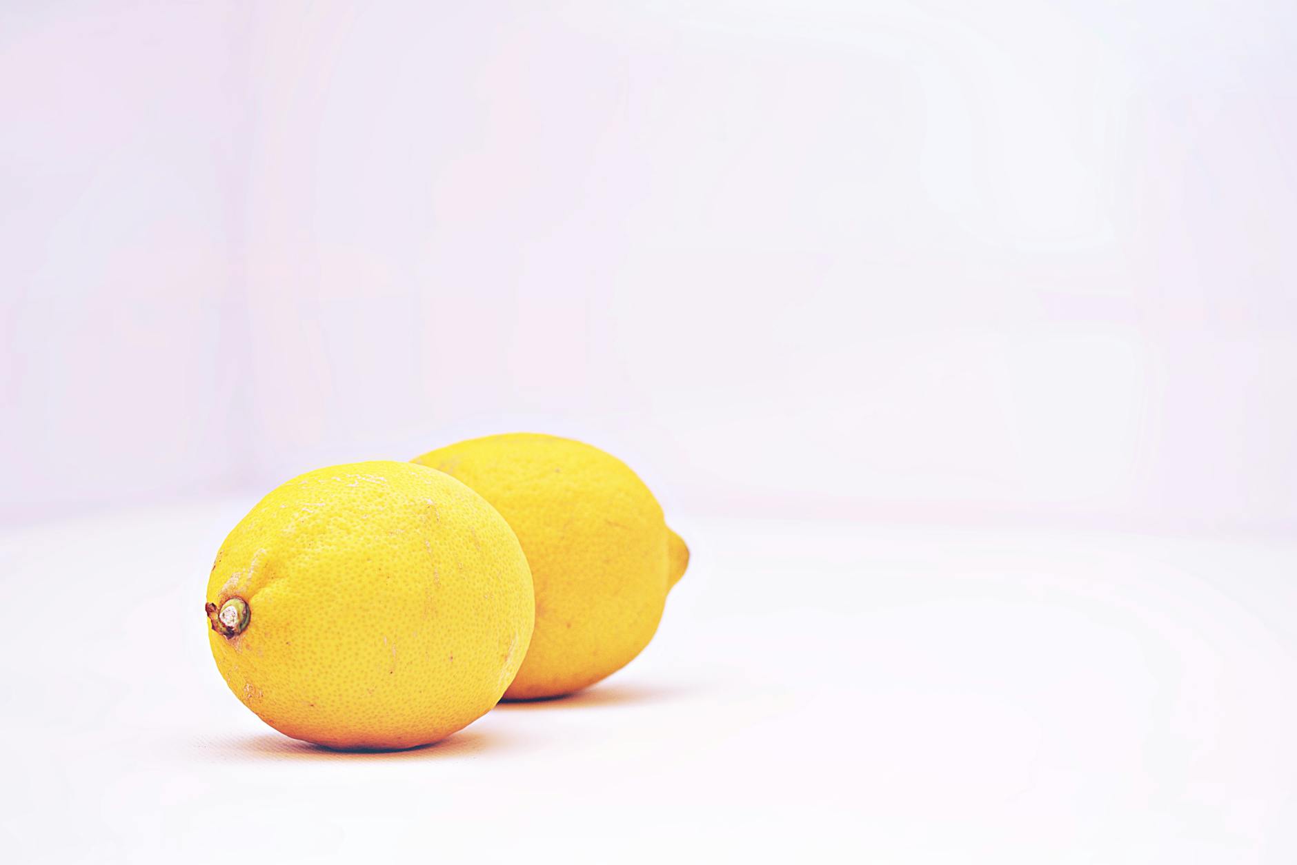 Bright yellow lemons on a pastel green background, symbolizing refreshed sensation and renewed pleasure