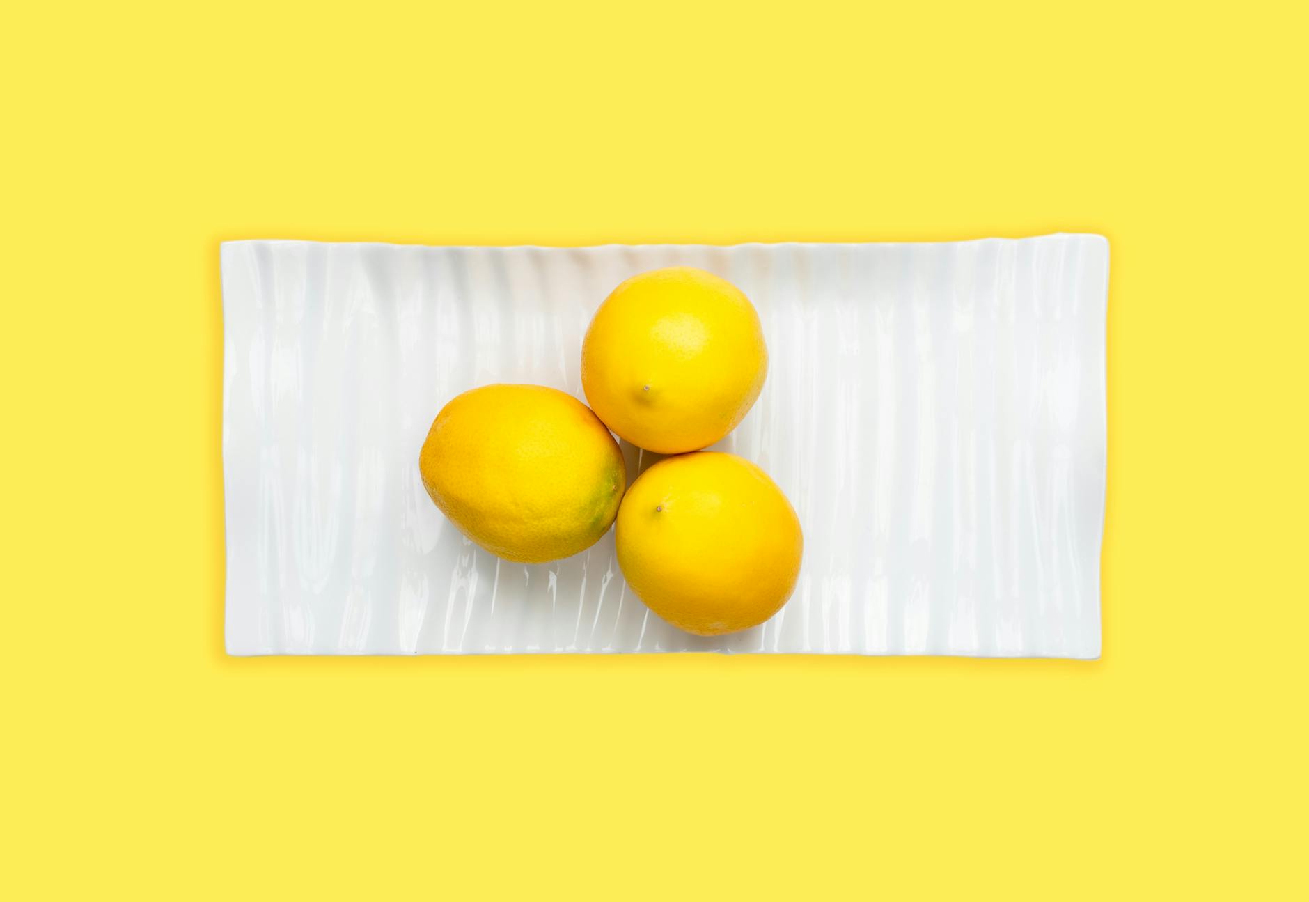 A hand holding a fresh lemon on a soft pink background, symbolizing new beginnings and fresh connection