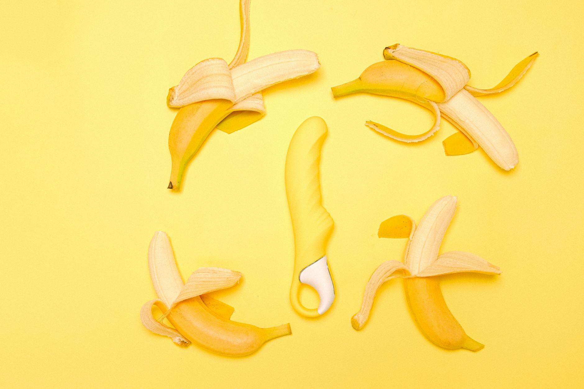 Yellow lemon vibrator surrounded by peeled lemons on a bright yellow background