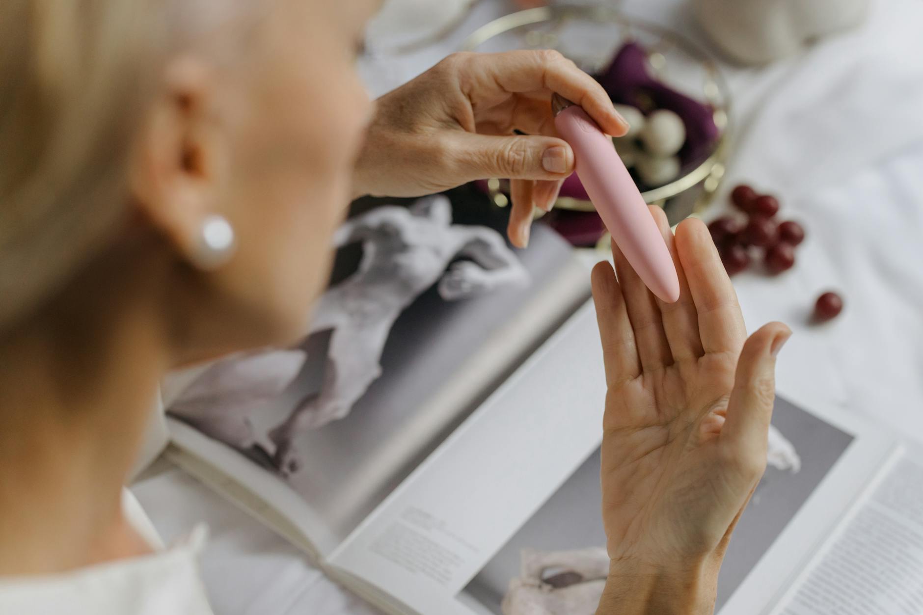 Close-up of a woman holding a lemon vibrator with art books in the background, emphasizing intimate and personal exploration.