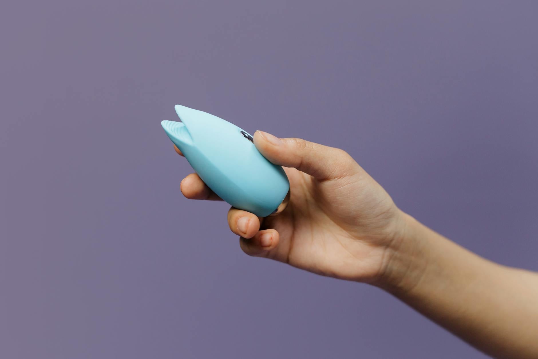 A blue silicone vibrator held in hand, representing modern couple intimacy solutions