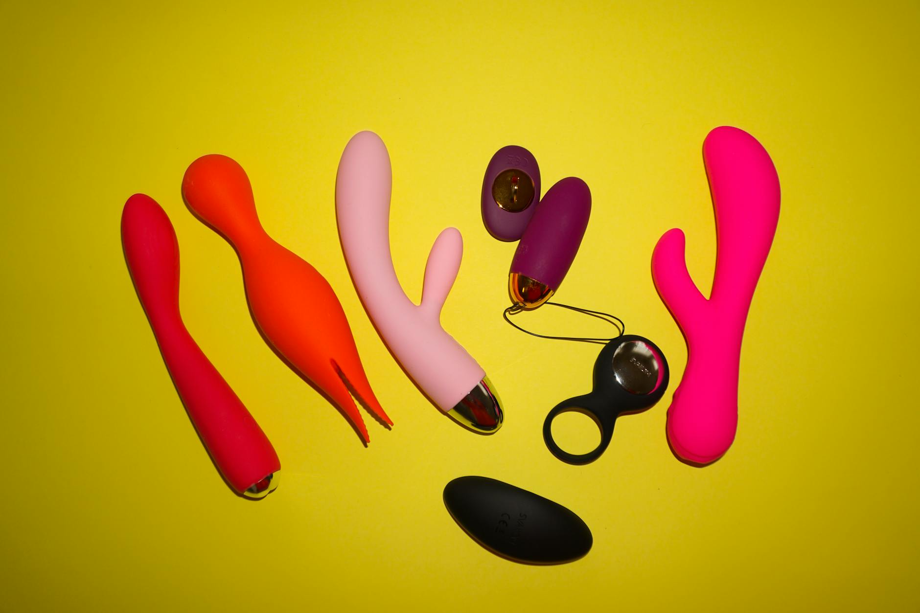 Colección colorida de juguetes sexuales silicona sobre fondo amarillo brillante